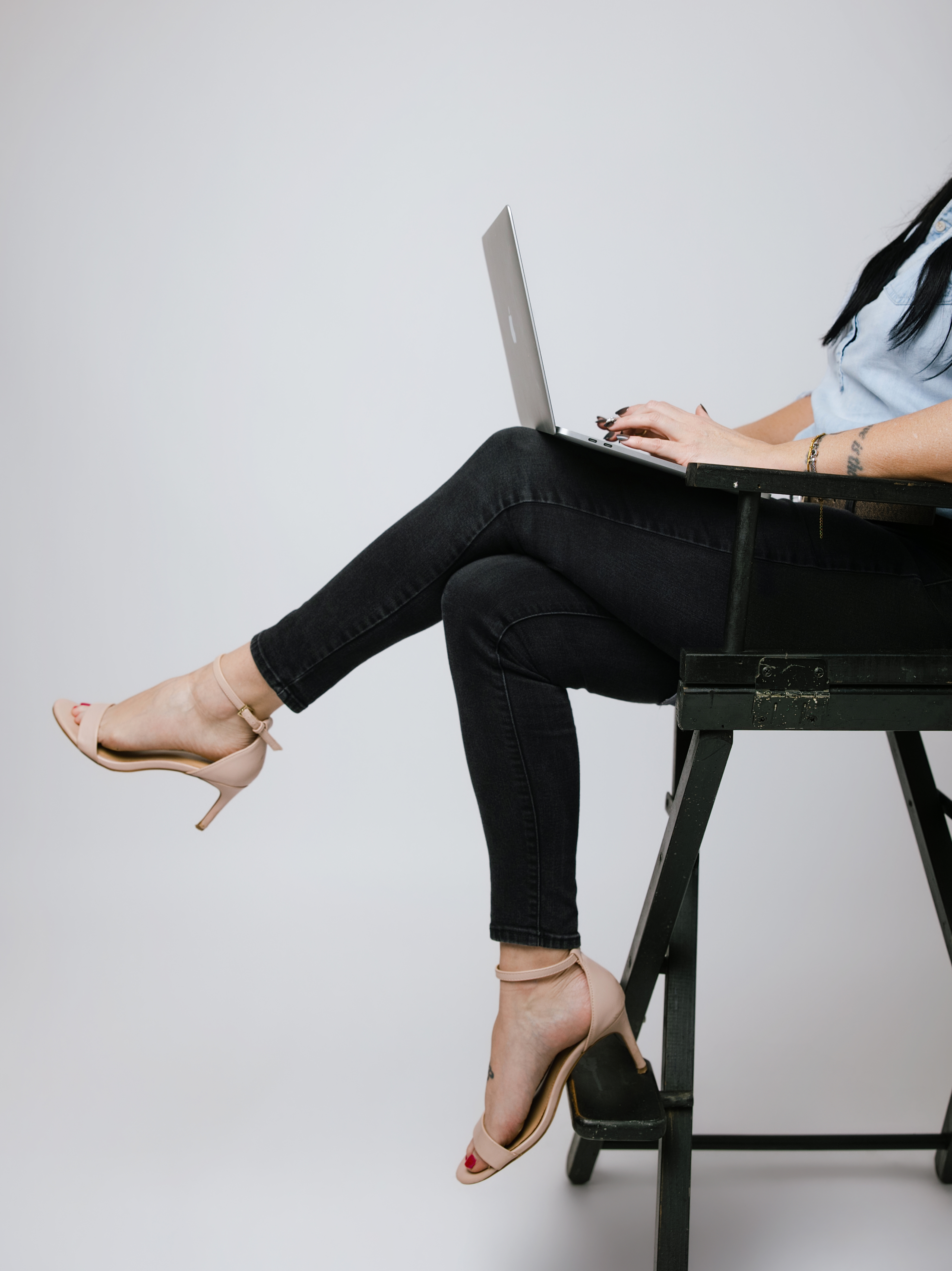 Close up of woman with a lap top in a chair and heels on
